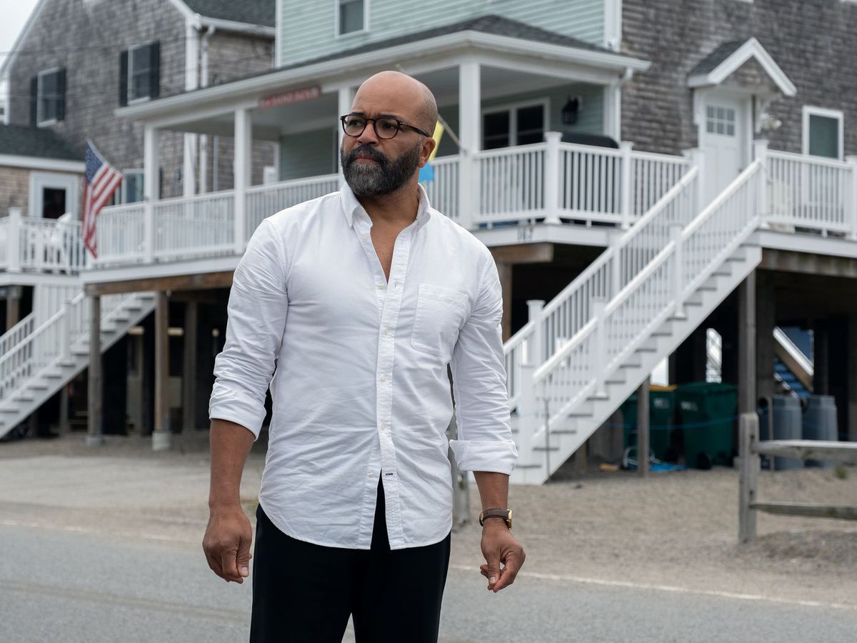 En man i en vit knäppt skjorta (Jeffrey Wright) som står framför upphöjda hus nära en strand i American Fiction.