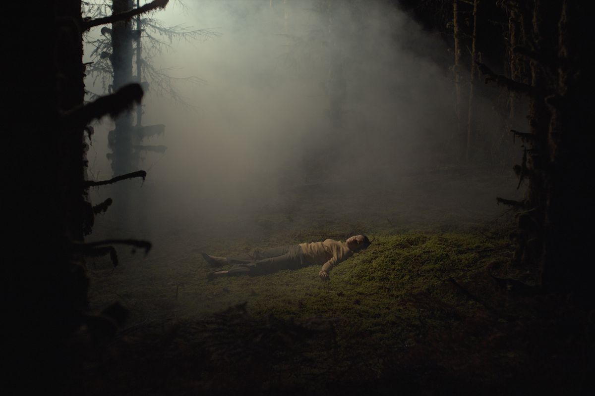 En kvinnas kropp som ligger mitt i en dimmig skog och ser fridfull ut 