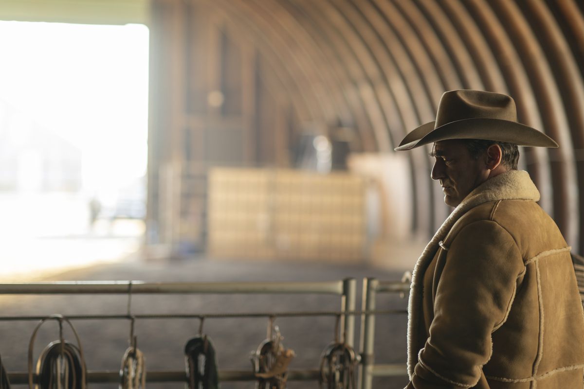 Jon Hamm i en stor shearling-rock och cowboyhatt tittar eftertänksamt över en gigantisk lada i säsong 5 av Fargo