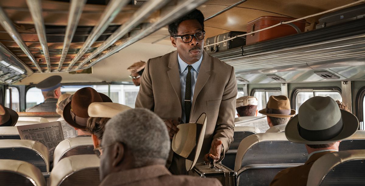 Colman Domingo, i en brun kostym med hatten i handen som Bayard Rustin, går ombord på en full buss i Netflix-filmen Rustin