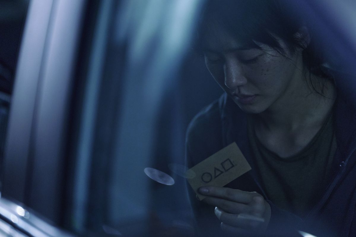 En ny, icke namngiven karaktär från Squid Game (Park Gyu-young) som håller ett visitkort som bjuder in henne till spelet