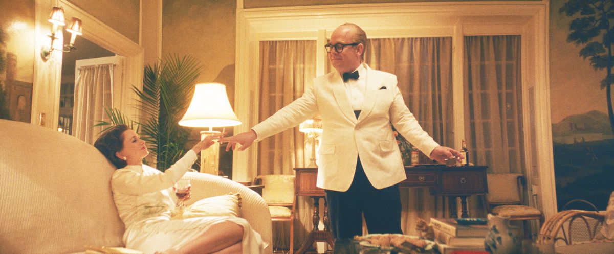 Capote, i en vit middagsjacka och fluga, står ovanför Babe Paley, slappar på en soffa i en vit klänning, medan han ger henne en cigarett i FX:s Feud: Capote vs. The Swans.