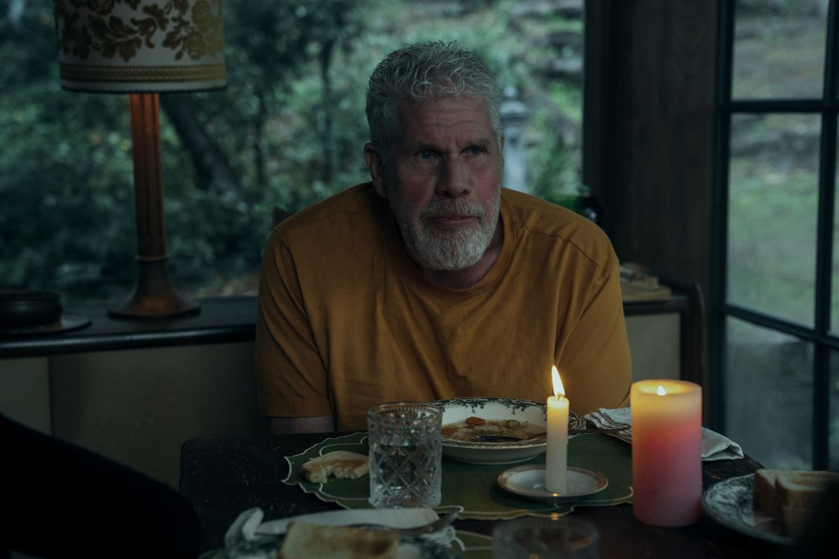 Ron Perlman ser ledsen ut i en gul T-shirt vid ett middagsbord med levande ljus i skymningen i Mr & Mrs Smith