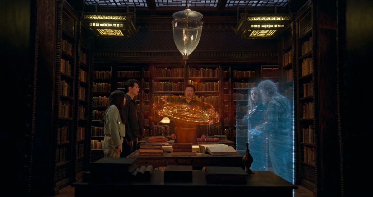 Shang-Chi, Katy, Wong, Captain Marvel, and Bruce Banner stand around a table, looking at a holographic render of the Ten Rings from Shang-Chi and the Ten Rings