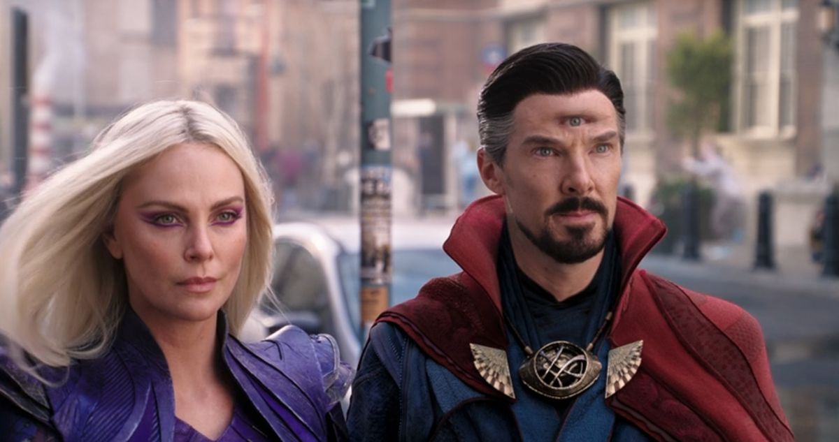 Clea (Charlize Theron) and Stephen Strange (Benedict Cumberbatch) look toward a portal on the streets of New York in a shot form Doctor Strange in the Multiverse of Madness. He’s got a third photorealistic eye on his forehead.