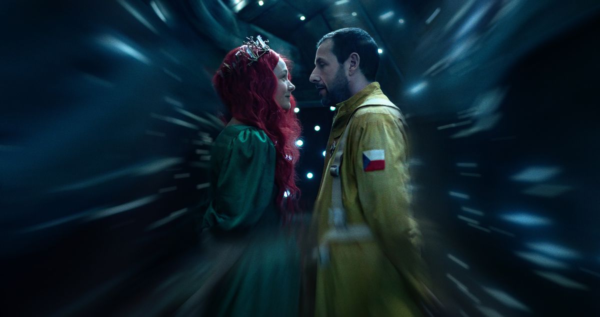 Lenka (Carey Mulligan, i silver diadem, flödande röd peruk och grön baldräkt) står nära Jakub (Adam Sandler), klädd som en astronaut i en gul flygdräkt, när allt omkring dem suddas ut i en scen från Netflix Spaceman