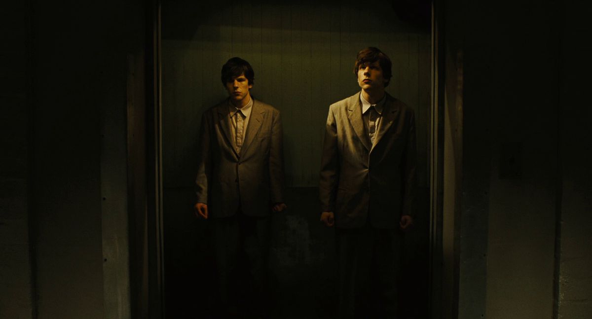 Två Jesses Eisenberg står tillsammans i en hiss i The Double