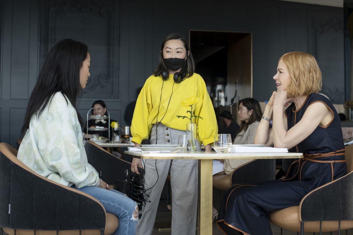 Lulu Wang står vid ett bord med Ji-young Yoo och Nicole Kidman bakom kulisserna på Expats