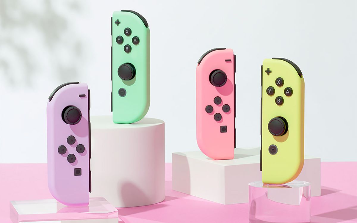 Fyra Nintendo Switch Joy-Cons i pastellfärger som står upprätt på ogenomskinliga vita och transparenta akrylstativ