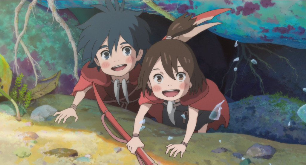 En blåhårig animepojke och en brunhårig animeflicka som bär röda kappor ler från under en sten i havet.