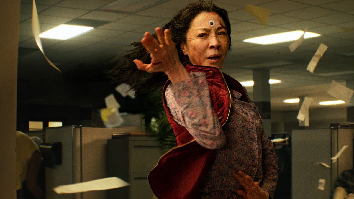 A bloodied Michelle Yeoh with a googly eye pasted on her forehead strikes a martial-arts pose in Everything Everywhere All at Once