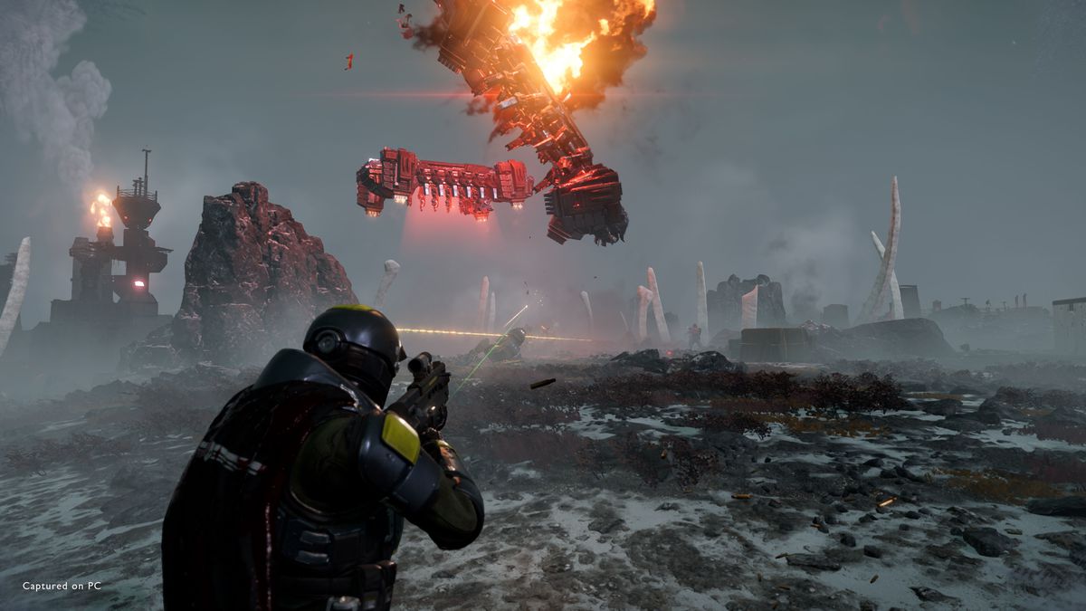 En Helldiver som skjuter på ett Automaton drop-fartyg som exploderar i lågor.