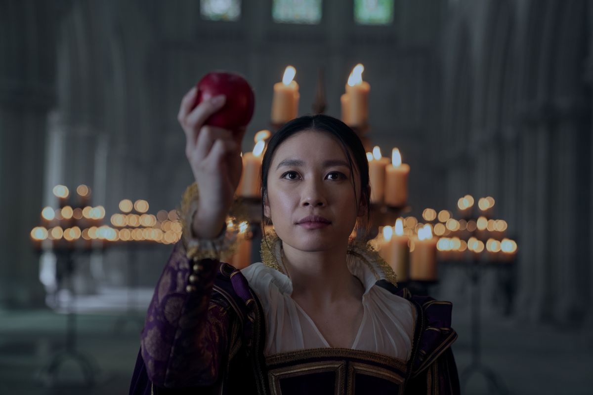 Jess Hong som Jin bär viktorianska kläder och håller upp ett äpple i ett tronrum
