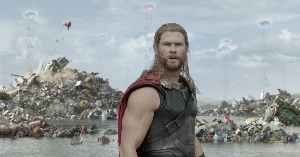 Thor ser sig förbryllad omkring i något som ser ut som en gigantisk sophög.  På himlen bakom honom kan portaler ses, med skräp som faller från dem till marken. 