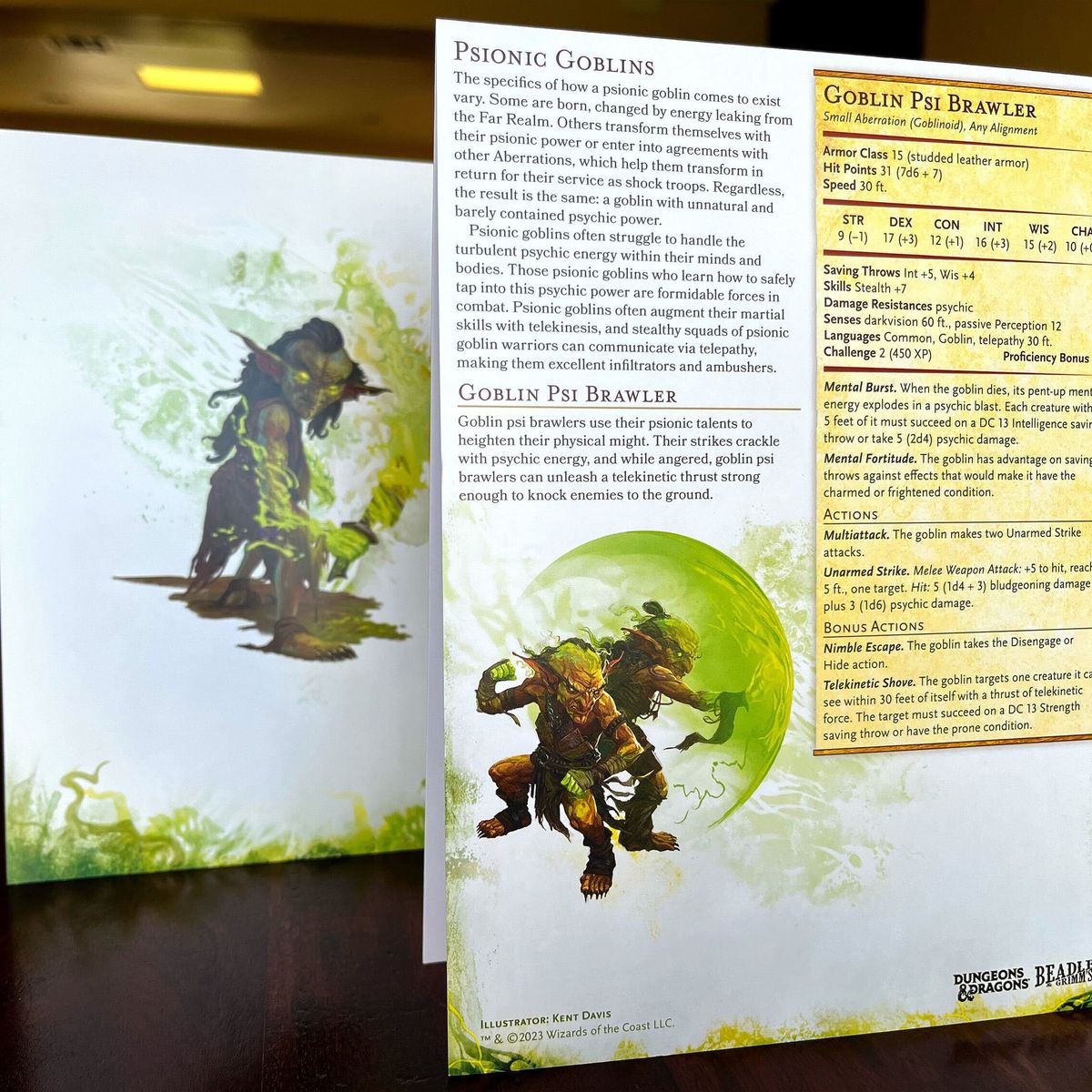 En utskrift av statistiska block för Psionic Goblins och Goblin Psi Brawlers sitter framför konstverk av en grön goblin som använder ett flammande svärd