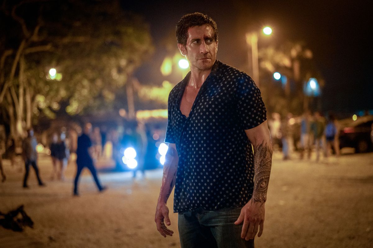 En man i en skjorta med knäppning som står på en gata på natten.
