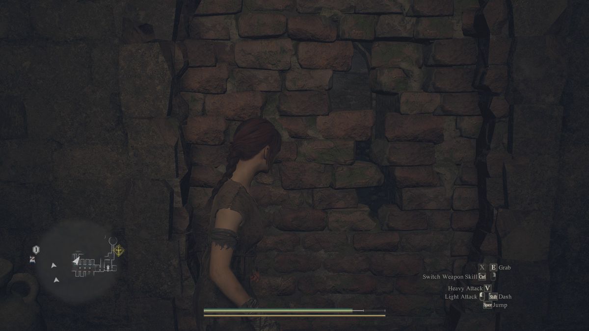 En Dragon's Dogma 2-hjälte tittar på en sönderfallande vägg i en fängelsecell.