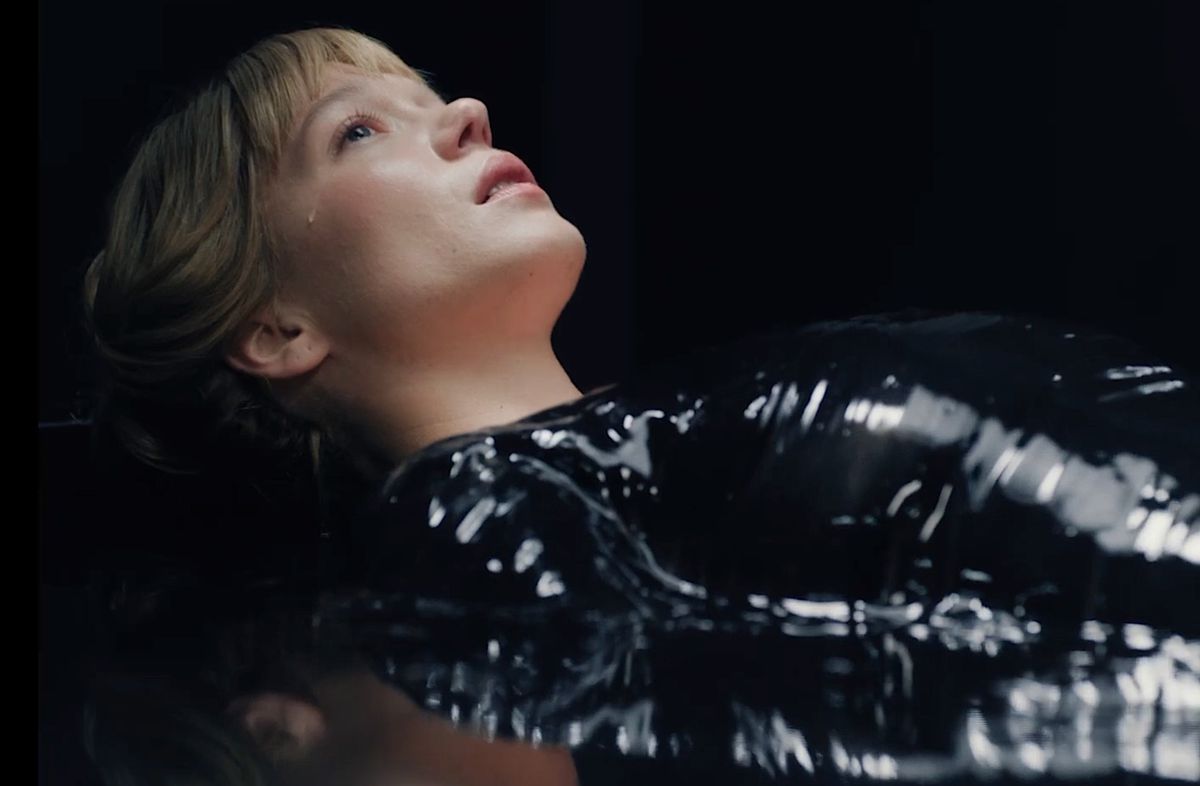 Gabrielle (Léa Seydoux), a pale young woman dressed in black vinyl, lies on her back staring upward with a tear rolling down her cheek in The Beast