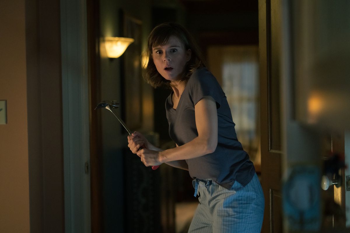 Katja Herbers, looking scared, holds up a hammer in defense in Evil