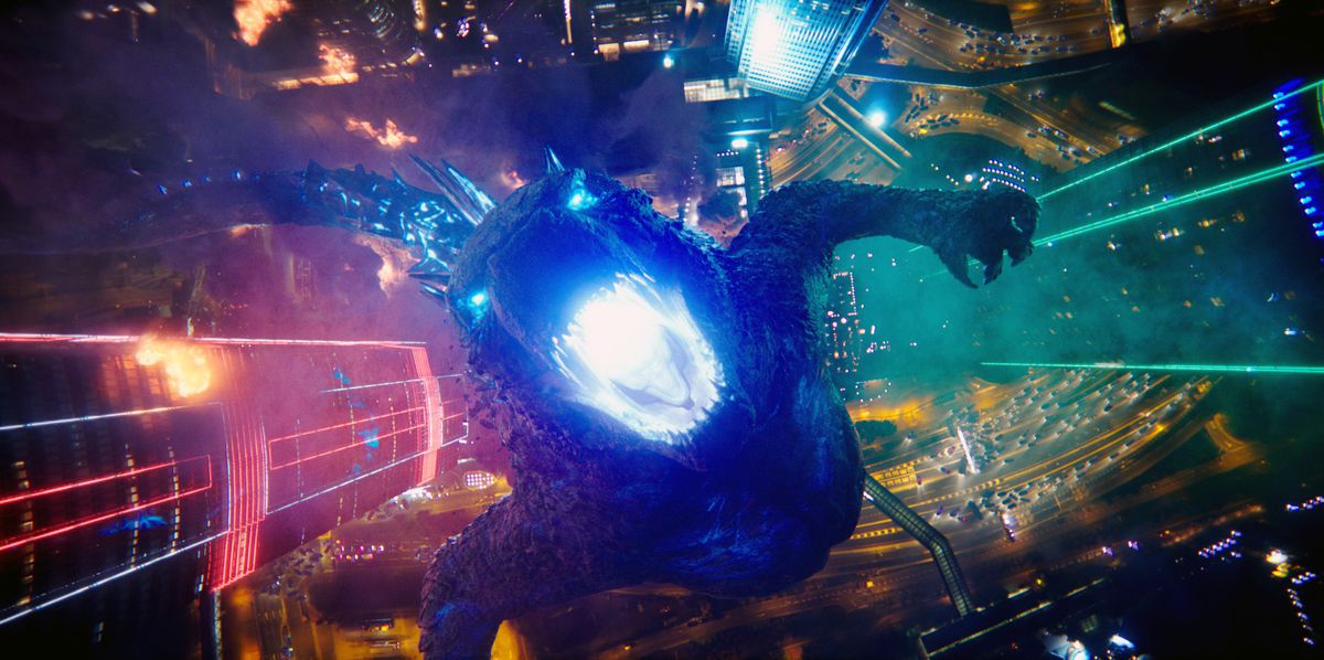 En bild uppifrån och ned av en rytande Godzilla som står i en neonupplyst stad ser rakt ner i hans blåglödande matstrupe i Godzilla Vs.  Kong