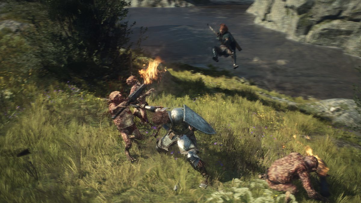 En krigare sticker en troll i halsen vid en flod i Dragon's Dogma 2. I bakgrunden siktar och hoppar en bågskytt
