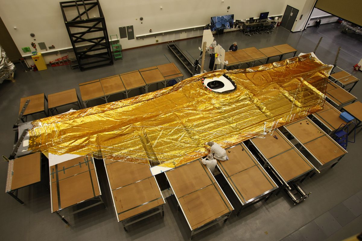 En femlagers solsköld i guld sträckt sig över en bit av rymdteleskopet James Webb som är utlagd på golvet
