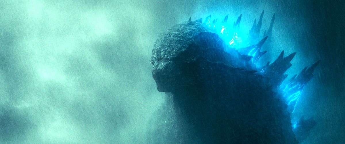 Godzilla ser grubblande och högtidlig ut med ögonen och munnen stängd, huvudet sänkt och ryggen glödande blå i Godzilla: King of the Monsters