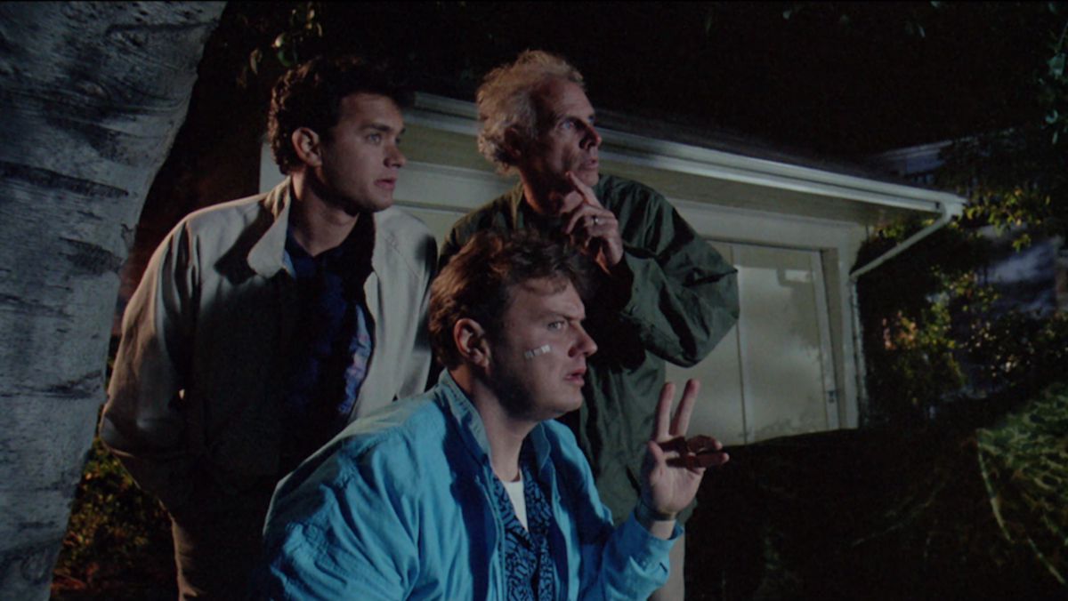 Tre män (LR Tom Hanks, Rick Ducommun, Bruce Dern) gömmer sig bakom en papperskorg på natten och stirrar på något utanför skärmen.
