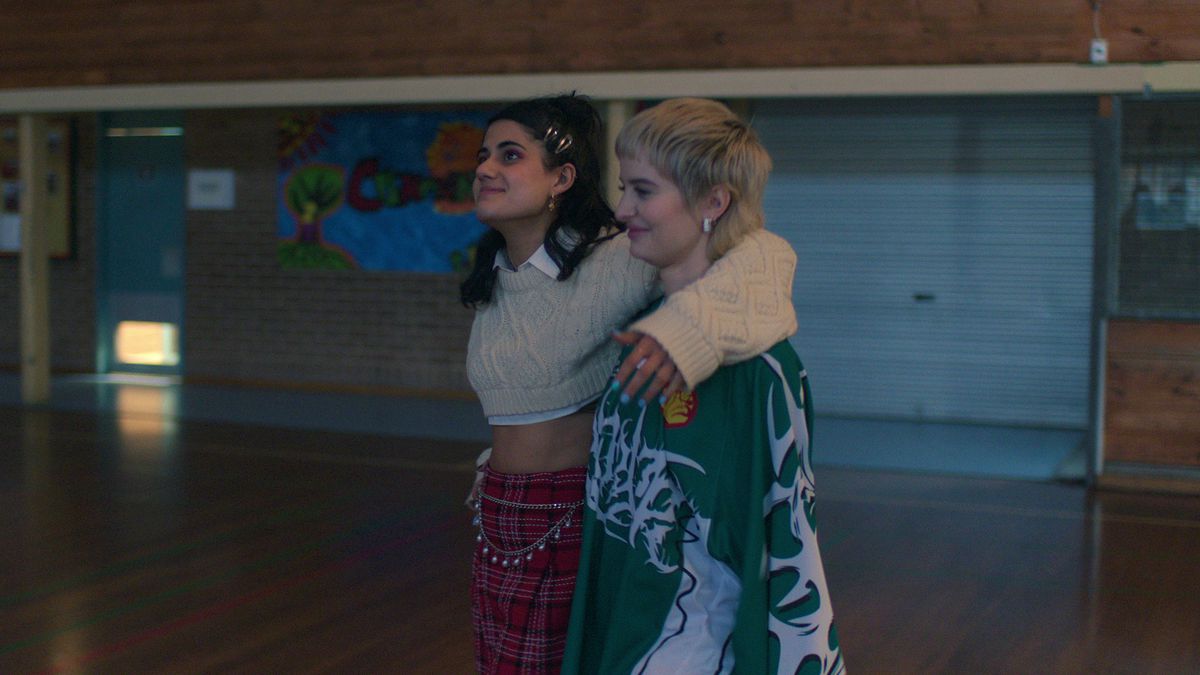 Two girls stand in a high school gym 