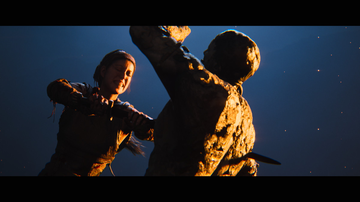 Senua grimaserar medan hon sticker en fiende med sitt svärd i Hellblade 2. De lyser hårt från höger mot en vanlig blå bakgrund.