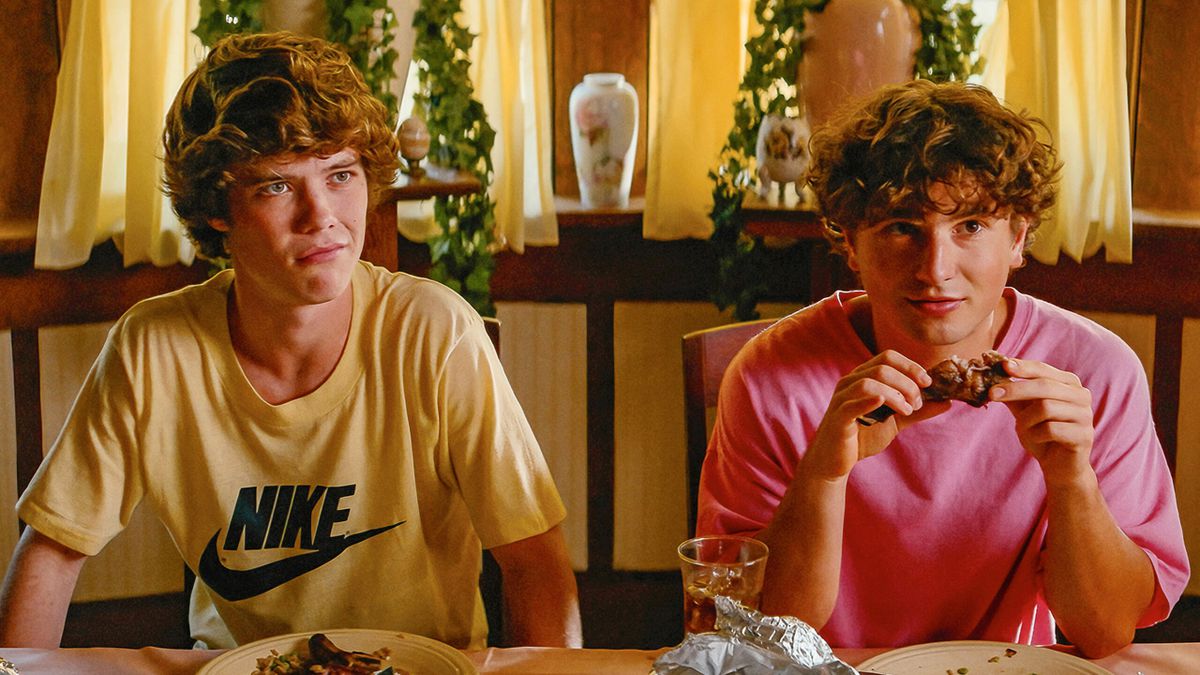 Two young men seated at a table eating a meal.