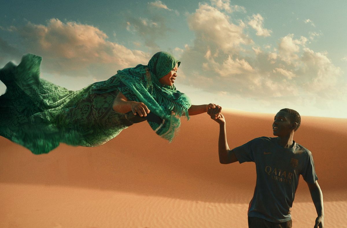A boy in a soccer jersey holding the hand of a floating woman dressed in an emerald shroud through the desert.