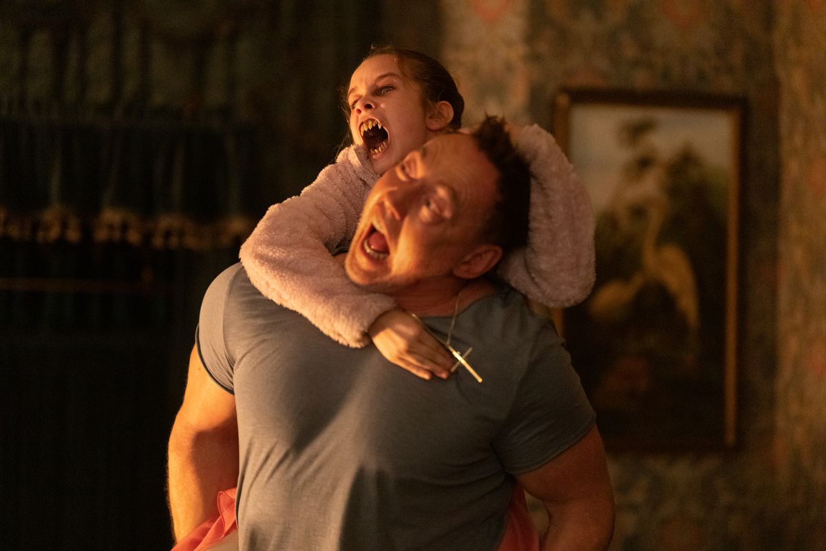 Alisha Weir håller fast i ryggen på Kevin Durand och försöker bita honom med sina vampyrskarpa tänder i Abigail