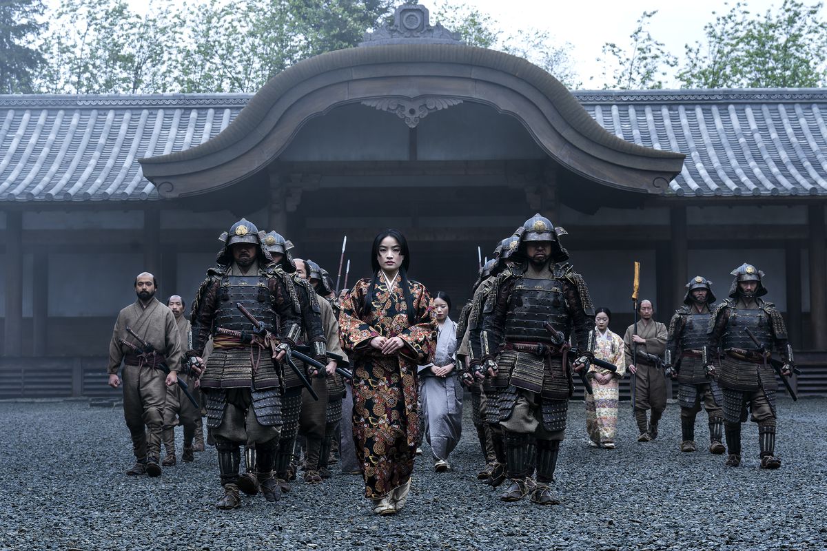 Anna Sawai flankeras av samurajer när hon går mot kameran i Shogun