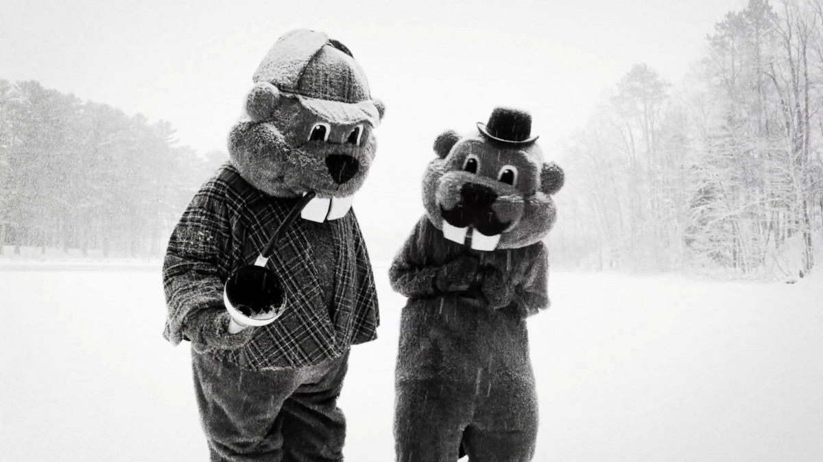 Två personer i bäverkostymer i maskotstorlek bär en Sherlock och Watson-dräkt i snön i Hundreds of Beavers