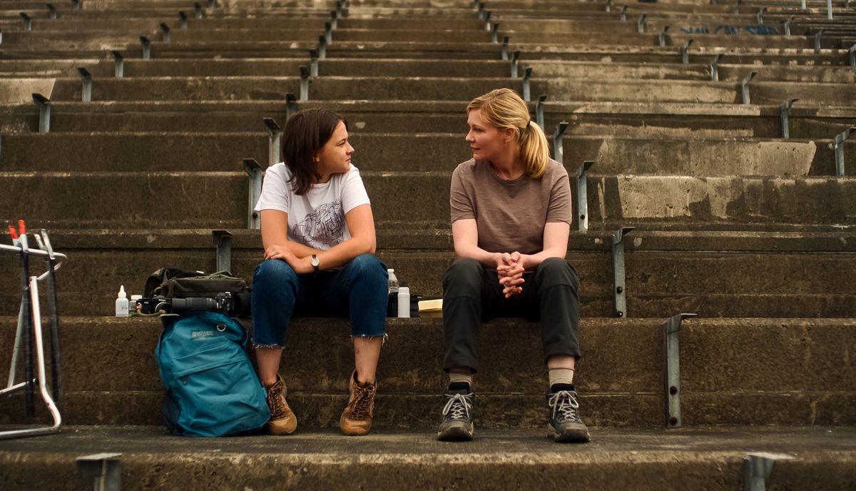 Fotojournalisterna Lee (Kirsten Dunst) och Jessie (Cailee Spaeny) sitter tillsammans på stenläktare, omgivna av sina kameror och utrustning, och möter varandra i Alex Garlands inbördeskrig