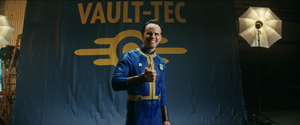 Cooper Howard (Walton Goggins) håller tummen upp i en Vault-Tec-kostym under en fotografering i en stillbild från Fallout avsnitt 3