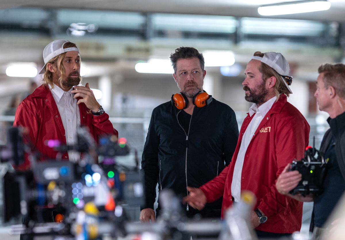Ryan Gosling och stuntartisten Logan Holladay, båda iklädda röda betjäningsjackor, pratar med David Leitch på inspelningen av The Fall Guy