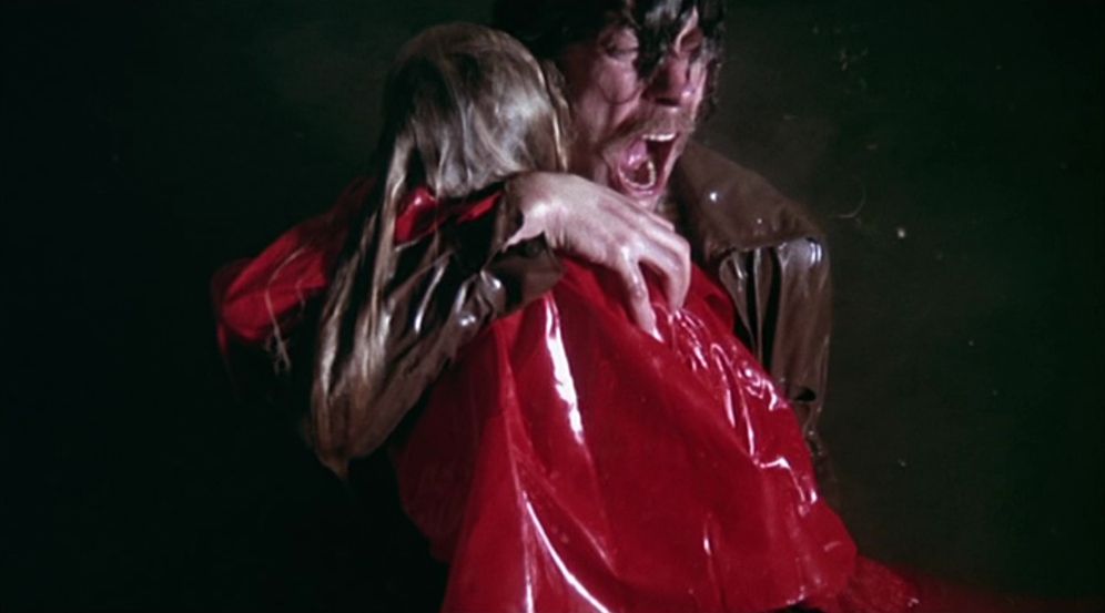 En man som skriker av smärta medan han håller kroppen av en ung flicka i en röd regnrock dränkt i vatten i Titta inte nu.