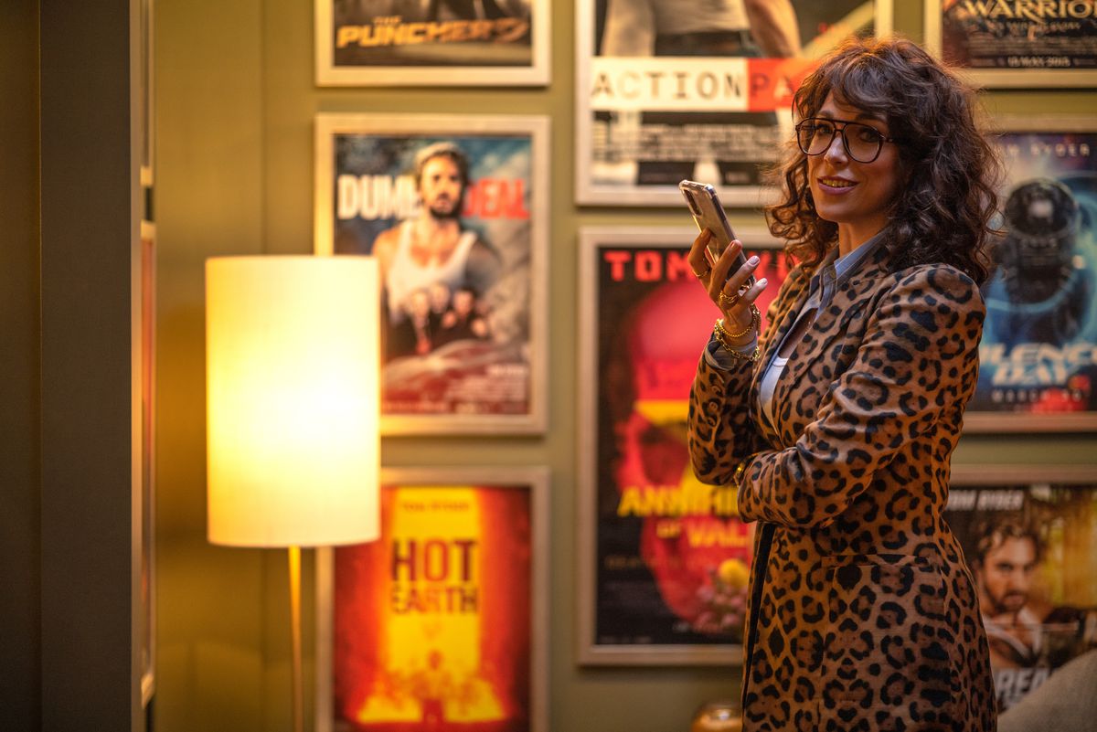 I en scen från The Fall Guy står producenten Gail Meyer (Hannah Waddingham, i en omlottklänning med leopardmönstrad) i ett rum kantat av filmaffischer och håller upp sin telefon