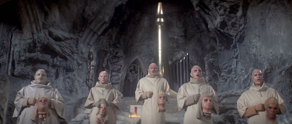 En grupp kala figurer klädda i munkkläder och med skyltdockorhuvuden i en grotta med en stor kyrkliknande interiör i Beneath the Planet of the Apes.