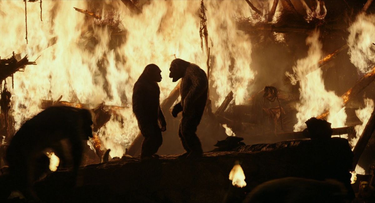 Två apor vända mot varandra på toppen av en plattform omgiven av apor som flyr från en brinnande struktur.