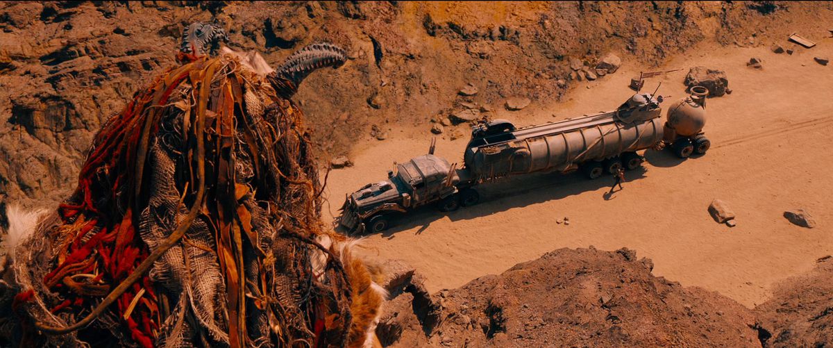 En stenryttare kikar över en klippa för att titta på Furiosa's War Rig i Mad Max: Fury Road