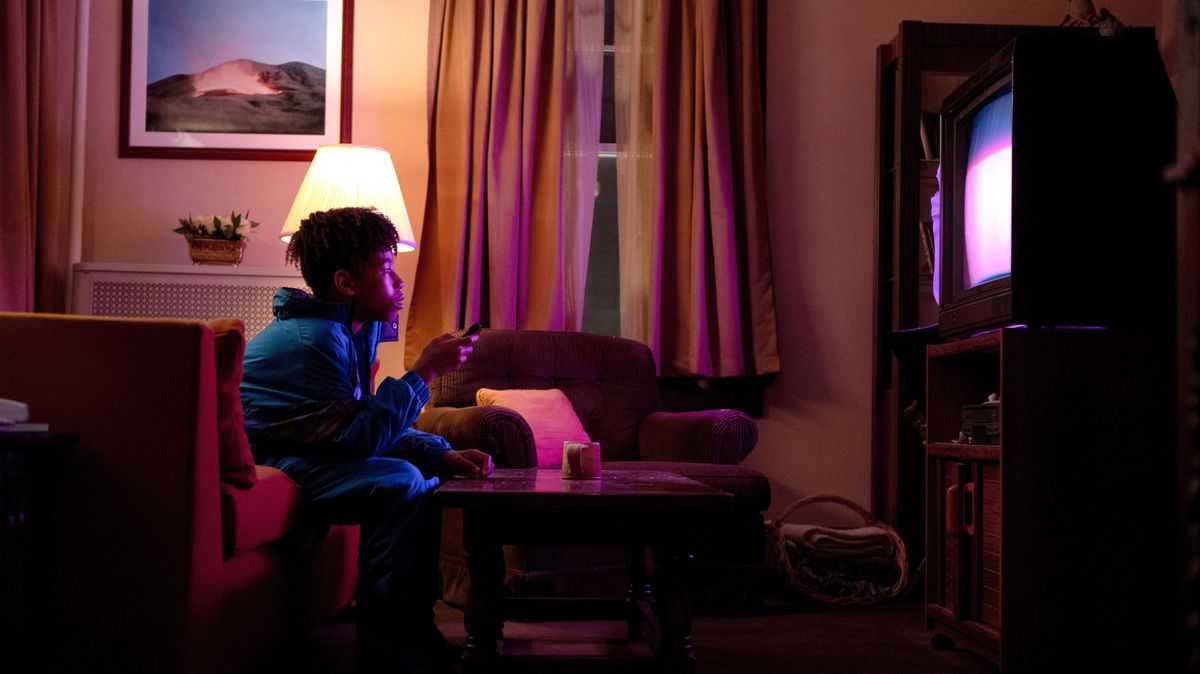Unga Owen (Ian Foreman) sitter på en röd soffa i ett mörkt vardagsrum och stirrar på TV:n i Jane Schoenbruns I Saw the TV Glow