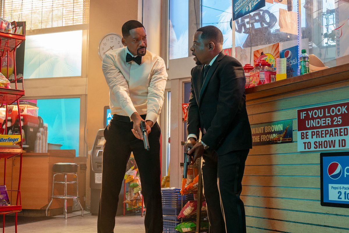 Will Smith and Martin Lawrence ready guns in Bad Boys: Ride or Die. They’re sharing a “look” as they stand in a bodega wearing somewhat bedraggled black tie formalwear. 