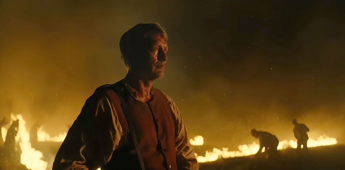 Mads Mikkelsen står framför ett brinnande landskap