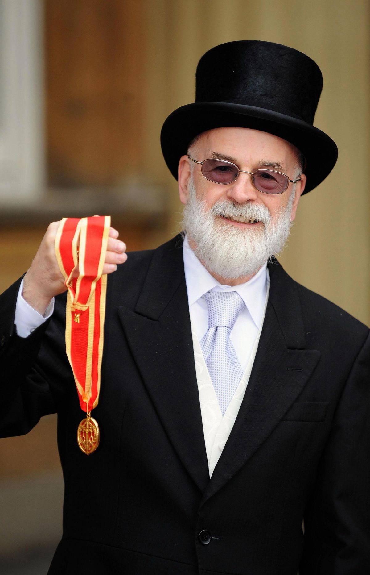 Sir Terry Pratchett visar sin riddarpris utanför Buckingham Palace.