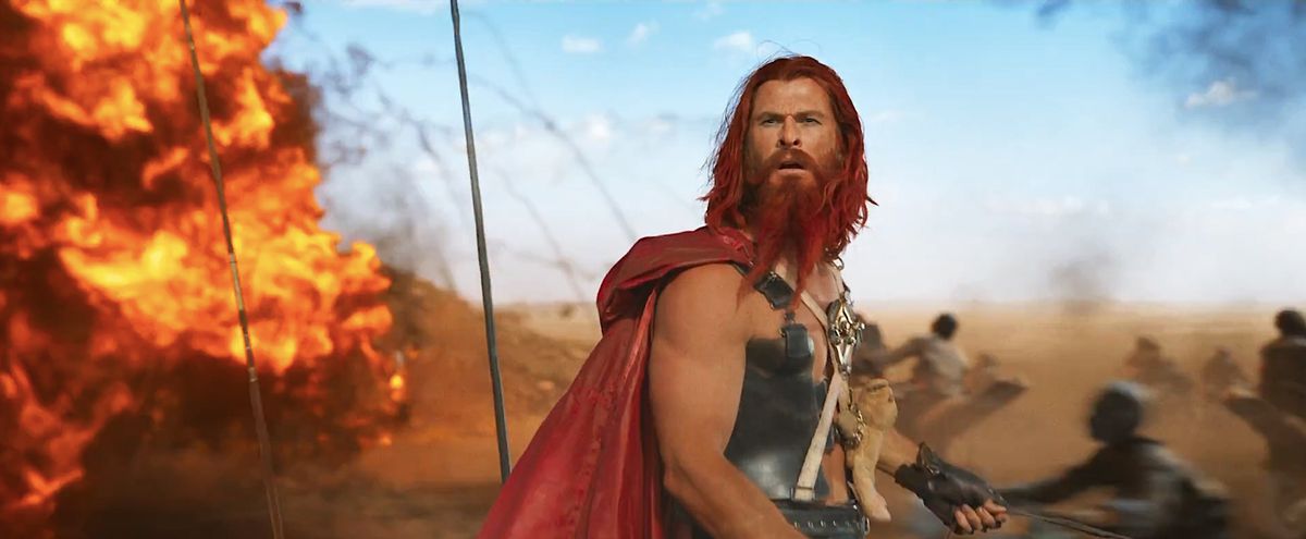 Krigsherren Dementus (Chris Hemsworth, i rödfärgat skägg och hår, med en lång röd cape och metallbröstplatta som påminner något om hans MCU Thor-dräkt, plus en nalle björn fastspänd på bröstet) står på ett slagfält med en explosion bakom sig. trailern för Furiosa