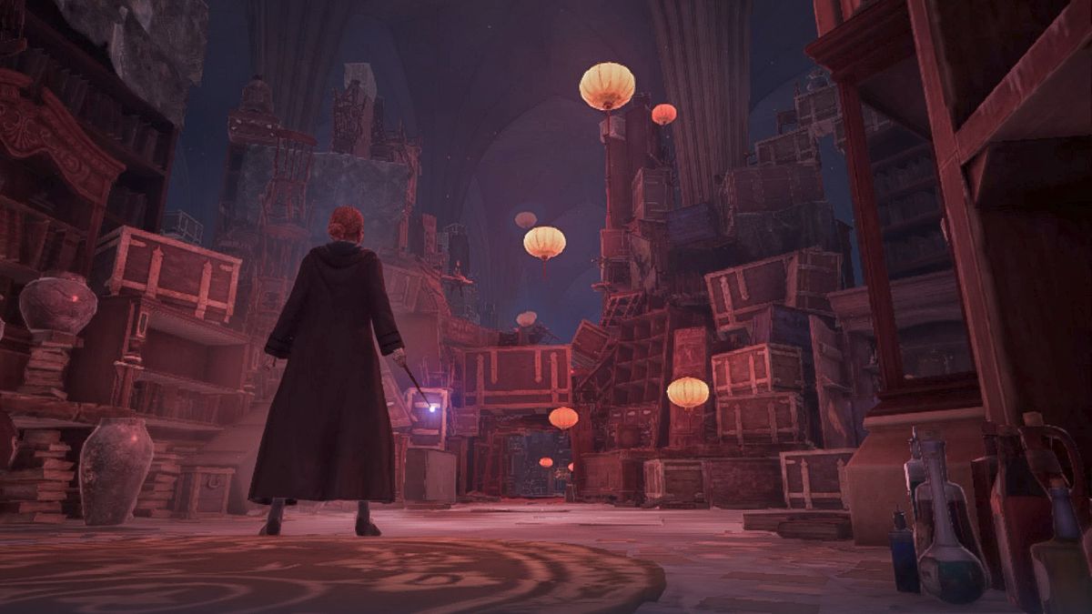 En ung trollkarl står i ett rum fullt av kistor i Nintendo Switch-versionen av Hogwarts Legacy