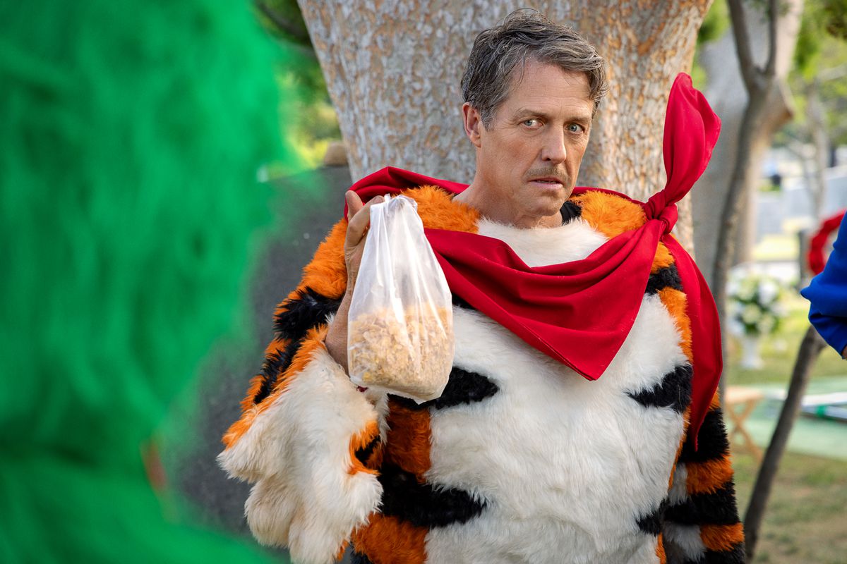 Hugh Grant bär mustasch och Tony the Tiger-dräkt med masken av i Netflix-filmen Unfrosted.